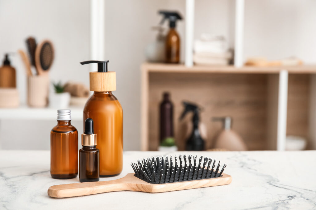 Hair brush and bottles of cosmetic products on table in room